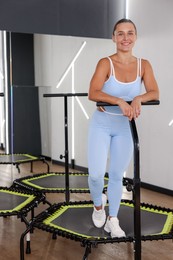 Photo of Smiling woman on mini exercise trampoline in fitness studio
