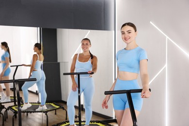 Photo of Smiling women on mini exercise trampolines in fitness studio