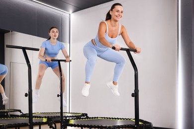 Photo of Young women jumping on mini exercise trampolines in fitness studio, low angle view