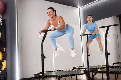Photo of Young women jumping on mini exercise trampolines in fitness studio, low angle view