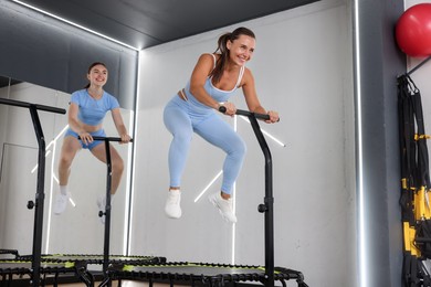 Photo of Young women jumping on mini exercise trampolines in fitness studio, low angle view