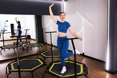 Photo of Smiling woman training on mini exercise trampoline in fitness studio