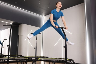 Photo of Happy woman jumping on mini exercise trampoline in fitness studio, low angle view