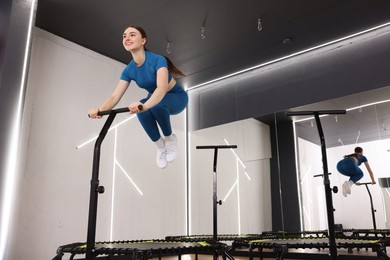 Photo of Smiling woman jumping on mini exercise trampoline in fitness studio, low angle view
