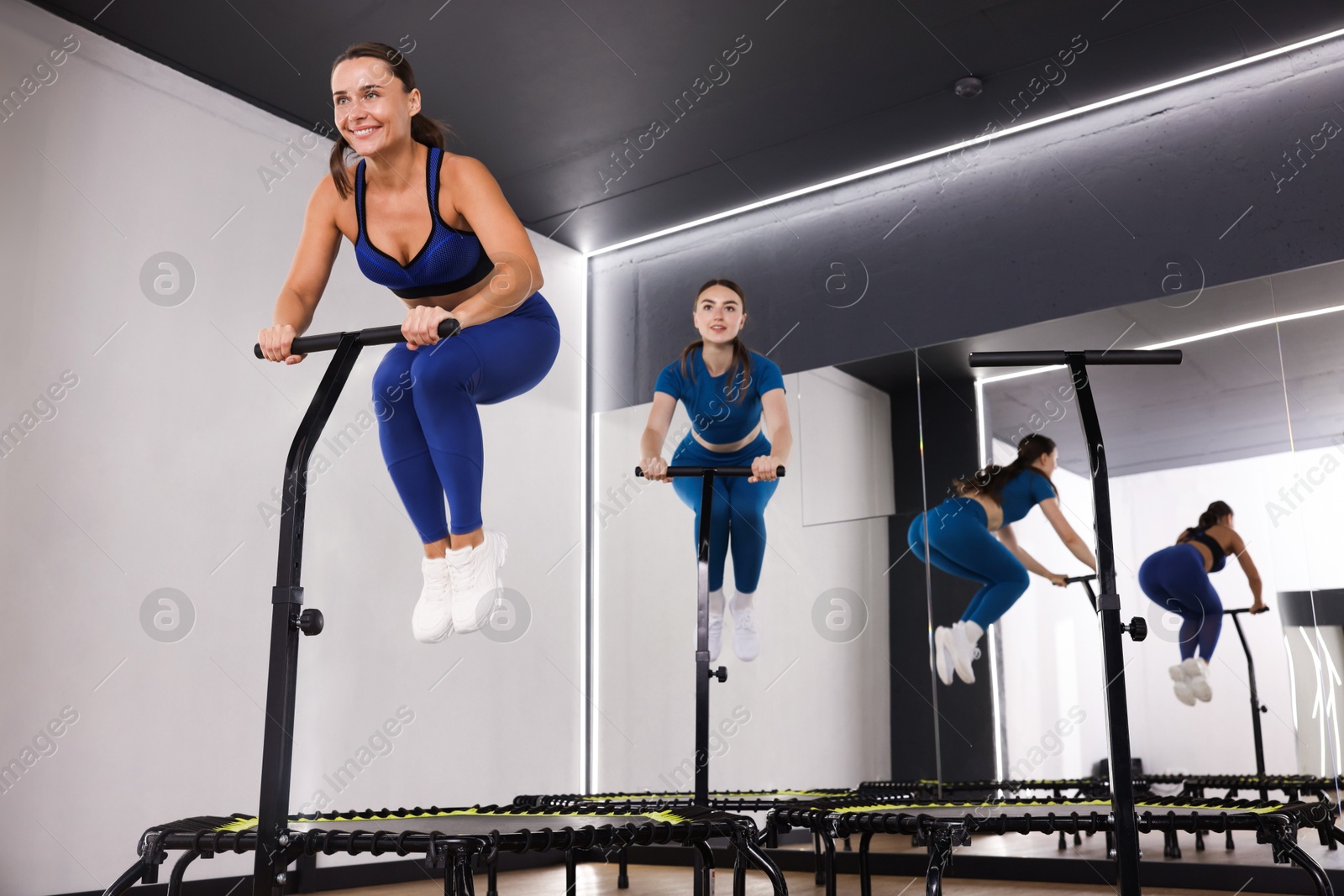 Young women jumping on mini exercise trampolines in fitness studio, low angle view Photo of Young women jumping on mini exercise trampolines in fitness studio, low angle view