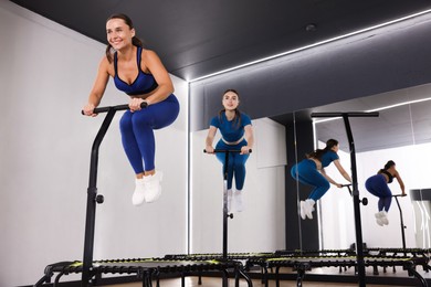 Photo of Young women jumping on mini exercise trampolines in fitness studio, low angle view