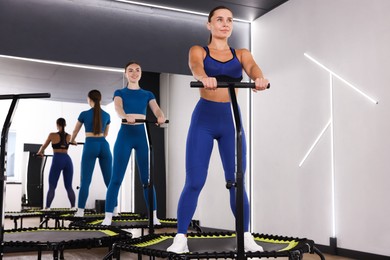 Photo of Young women on mini exercise trampolines in fitness studio, low angle view