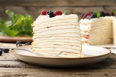 Photo of Piece of tasty crepe cake with berries served on wooden table, closeup