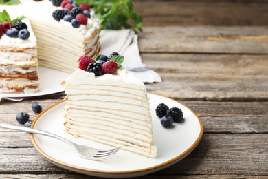 Photo of Piece of tasty crepe cake with berries served on wooden table, closeup. Space for text