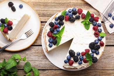 Photo of Tasty crepe cake with berries on wooden table, flat lay