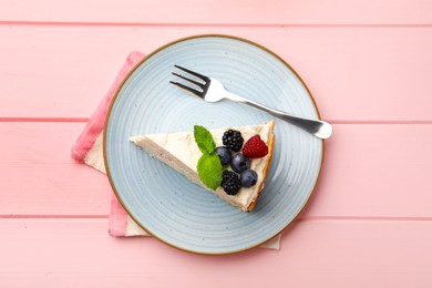 Photo of Piece of tasty crepe cake with berries served on pink wooden table, top view