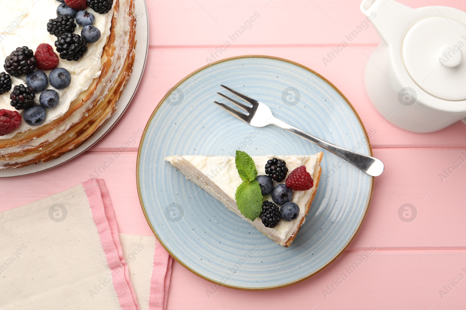 Photo of Piece of tasty crepe cake with berries served on pink wooden table, flat lay