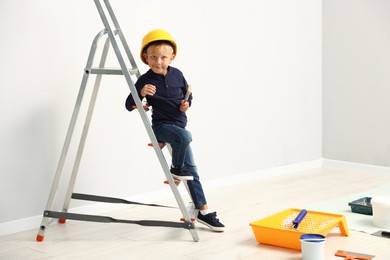 Photo of Choice of profession. Little boy with paint brush pretending to be painter indoors. Space for text