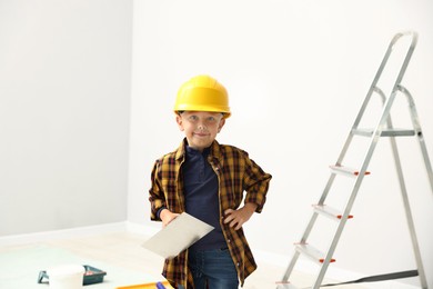 Photo of Choice of profession. Little boy with spatula tool pretending to be builder indoors