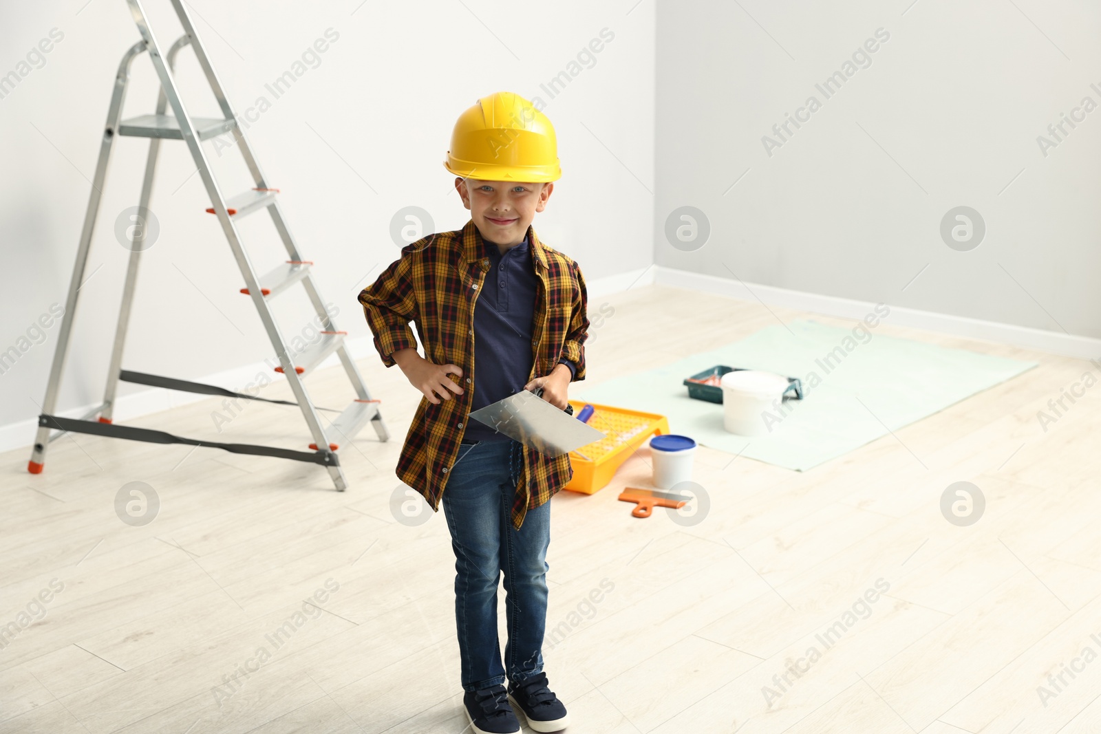 Photo of Choice of profession. Little boy with spatula tool pretending to be builder indoors