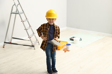 Photo of Choice of profession. Little boy with spatula tool pretending to be builder indoors