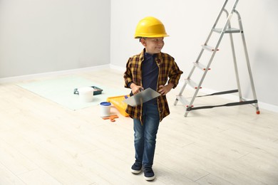 Photo of Choice of profession. Little boy with spatula tool pretending to be builder indoors