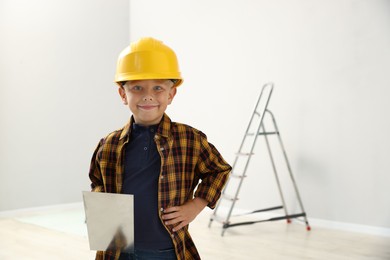 Photo of Choice of profession. Little boy with spatula tool pretending to be builder indoors