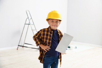 Photo of Choice of profession. Little boy with spatula tool pretending to be builder indoors