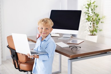 Photo of Choice of profession. Little boy pretending to work on laptop in office