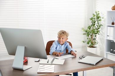 Photo of Choice of profession. Little boy pretending to work on computer in office