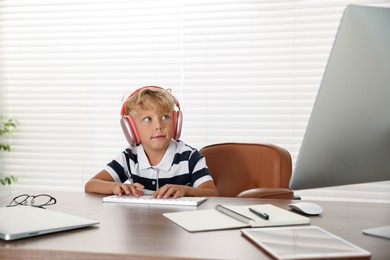 Photo of Choice of profession. Little boy with headphones pretending to work on computer in office