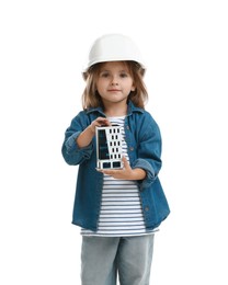 Photo of Choice of profession. Little girl in hardhat with building model pretending to be architect on white background