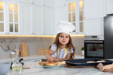 Photo of Choice of profession. Little girl with pastries pretending to be chef in kitchen