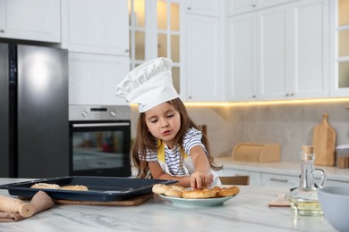 Photo of Choice of profession. Little girl with pastries pretending to be chef in kitchen