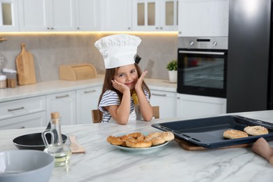 Photo of Choice of profession. Little girl with pastries pretending to be chef in kitchen