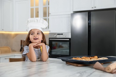 Photo of Choice of profession. Little girl with pastries pretending to be chef in kitchen