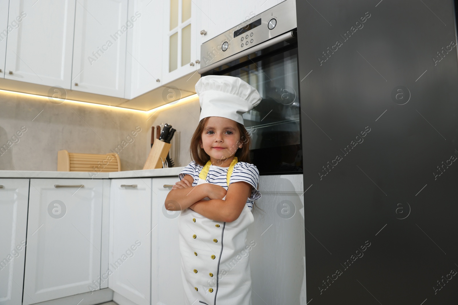 Photo of Choice of profession. Little girl pretending to be chef in kitchen