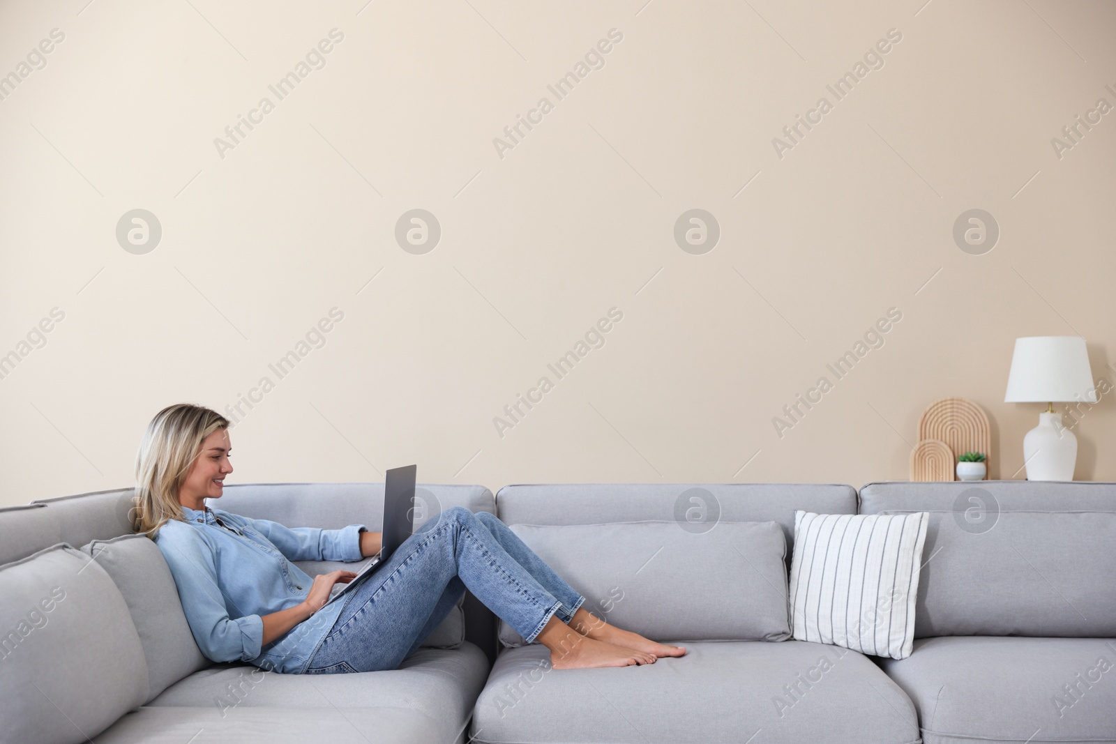 Beautiful woman using laptop on sofa at home. Space for text Photo of Beautiful woman using laptop on sofa at home. Space for text