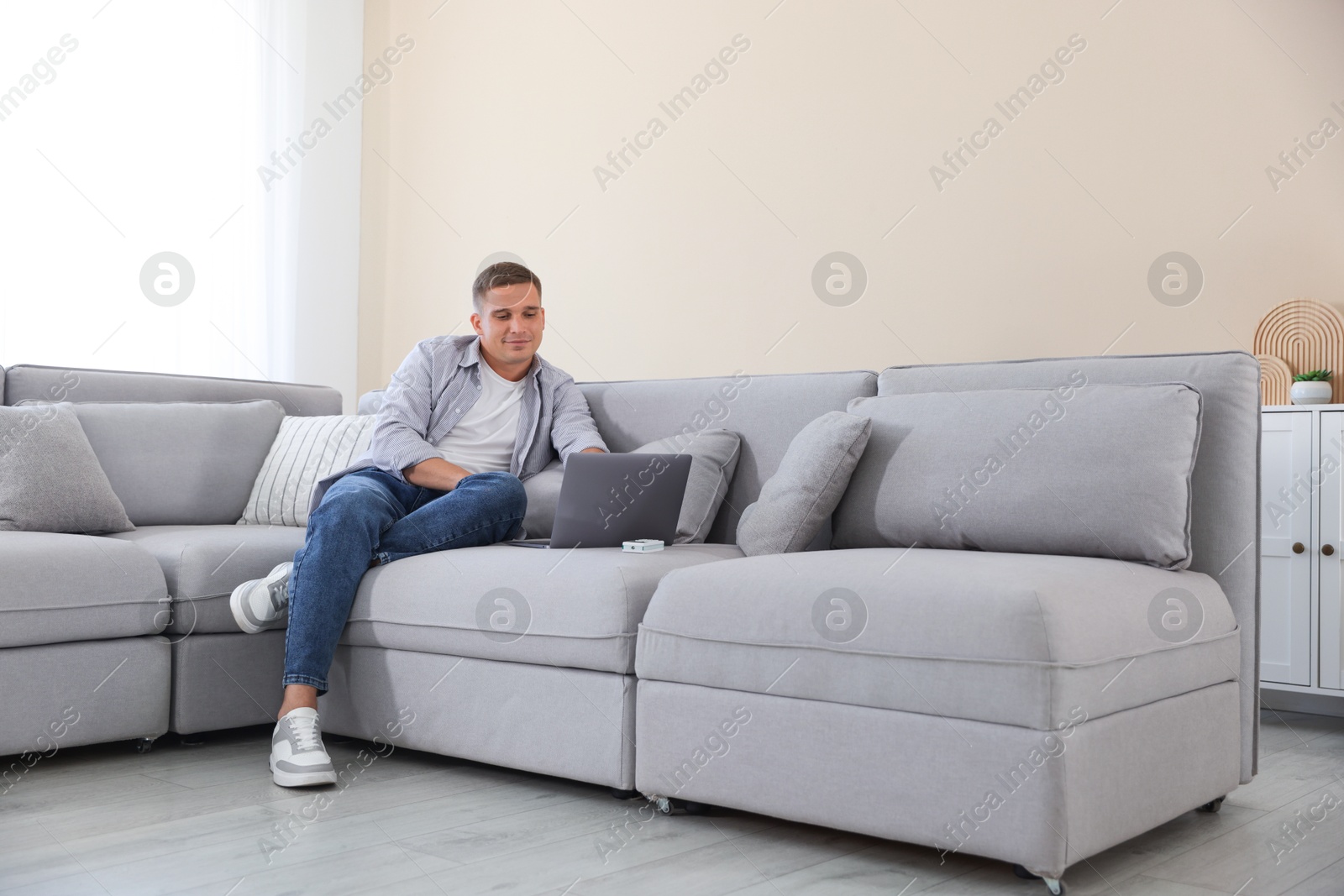 Young man using laptop on sofa at home Photo of Young man using laptop on sofa at home