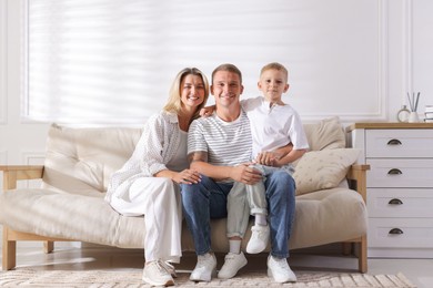 Photo of Happy parents and their son on sofa at home