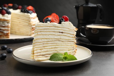 Photo of Piece of tasty crepe cake with berries served on grey table, closeup