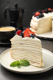 Photo of Piece of tasty crepe cake with berries served on grey table, closeup