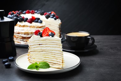Photo of Piece of tasty crepe cake with berries served on grey table, closeup