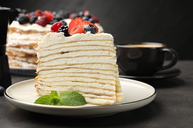 Photo of Piece of tasty crepe cake with berries served on grey table, closeup