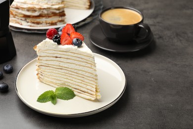 Photo of Piece of tasty crepe cake with berries served on grey table, closeup