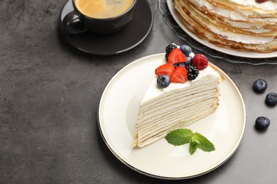 Photo of Piece of tasty crepe cake with berries served on grey table
