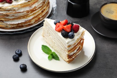 Photo of Piece of tasty crepe cake with berries served on grey table