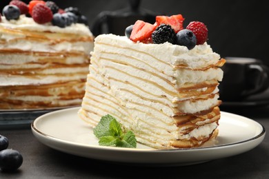 Photo of Piece of tasty crepe cake with berries on grey table, closeup