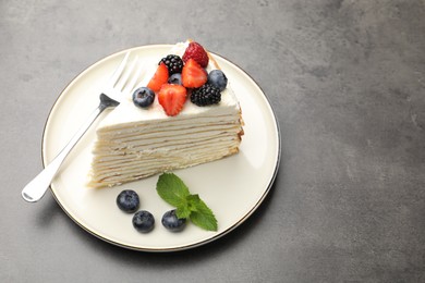 Photo of Piece of tasty crepe cake with berries on grey table. Space for text