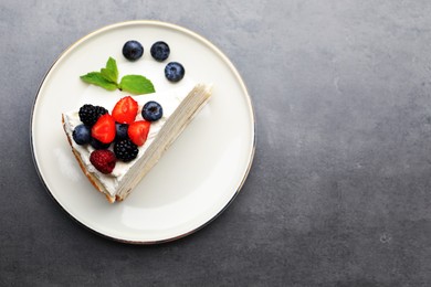 Photo of Piece of tasty crepe cake with berries on grey table, top view. Space for text