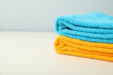 Photo of Colorful fresh terry towels on white table, closeup. Space for text