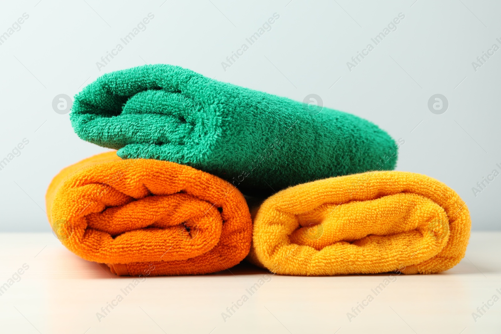 Photo of Colorful fresh terry towels on white table, closeup