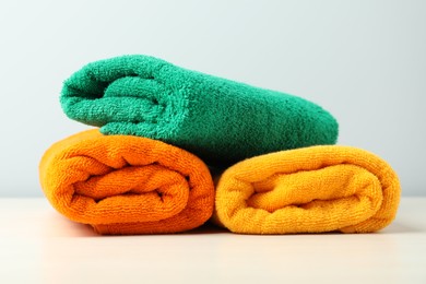 Photo of Colorful fresh terry towels on white table, closeup