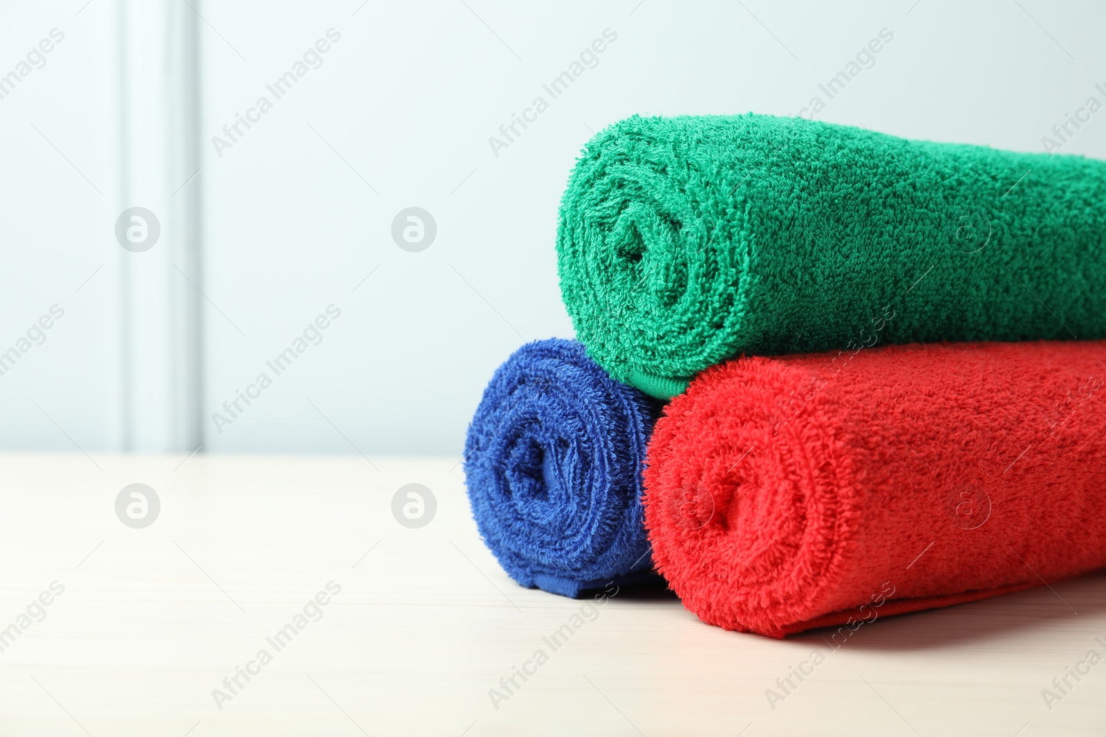 Photo of Colorful fresh terry towels on white table, closeup. Space for text