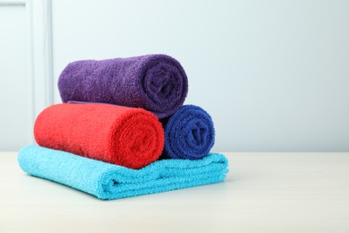 Photo of Colorful fresh terry towels on white table. Space for text